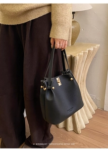 Detail of black lychee grain leather bucket bag with gold hardware and side rivets
