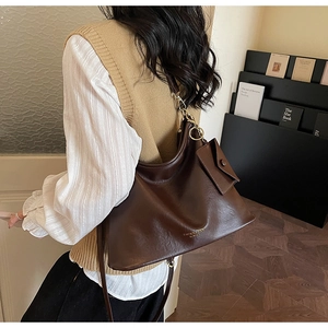 Detail of deep brown retro leather tote bag with small magnetic pouch and gold hardware
