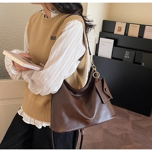 Detail of a dark brown glossy leather tote bag with a small matching zip coin purse