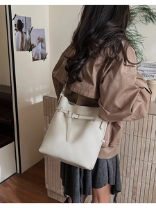Detailed macro view of large cream leather bucket bag with silver buckle and pebbled texture