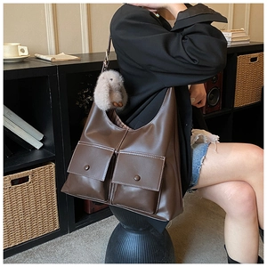 Detail of dark brown tote bag featuring large pockets and contrasting white stitching