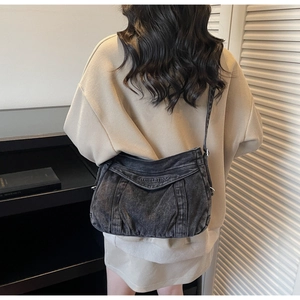 Detail of dark grey washed denim crossbody bag with embroidered logo on the flap