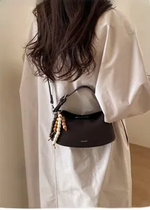 Detail of dark brown lychee leather handbag with a colorful wooden beaded tassel charm