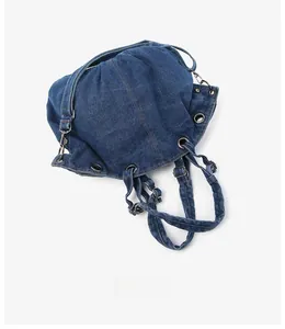 Detail of dark blue denim drawstring bag showing metal eyelets and washed fabric texture