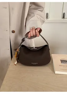 Close-up of dark brown lychee leather hobo bag with wood bead tassel in a cozy setting