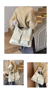 Detail of cream hobo bag with front flap pockets and cute plush rabbit charm accessory