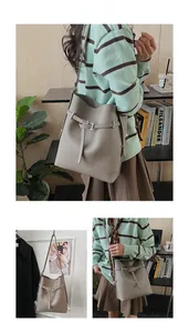 Detail of the grey bucket bag showing litchi grain texture and adjustable strap