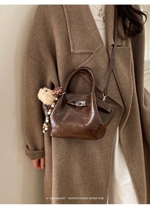 Gros plan d'un sac seau rétro marron foncé en cuir brillant avec pendentif chien en peluche