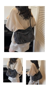 Detail of dark denim crossbody bag with vintage washed texture and embossed lettering