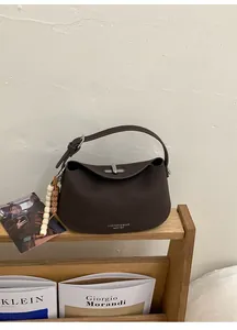 Detail of coffee brown leather bag with lychee texture and silver metal twist lock