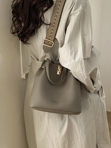 Brown lychee leather bucket bag with jacquard strap shown on model's shoulder