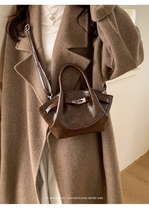 Sac seau rétro marron en cuir huilé brillant porté avec un manteau chic kaki