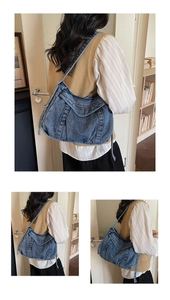 Detail of vintage blue denim hobo bag featuring white logo embroidery and contrast stitching