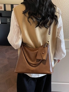 Brown leather shoulder bag with small pouch shown on model in a vintage indoor setting