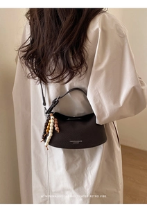 Detail of coffee brown pebble leather shoulder bag with colorful wooden bead charm