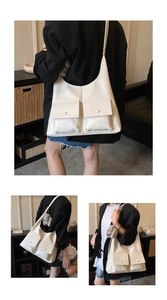 Detail view of cream oversized hobo tote bag featuring dual front pockets and bunny charm