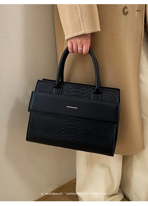 Detail of black crocodile texture handbag with Fashion & Bag logo and round handles