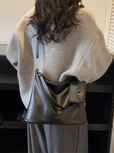 Classic black leather tote bag with small pouch shown on shoulder for daily commute