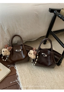 Détail du sac seau marron foncé avec boucle métallique et breloque ours en peluche