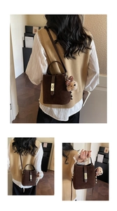 Detail of dark brown matte bucket bag with golden square clasp and cute bear charm
