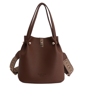 Brown lychee leather bucket bag with gold lock and colorful woven wide shoulder strap
