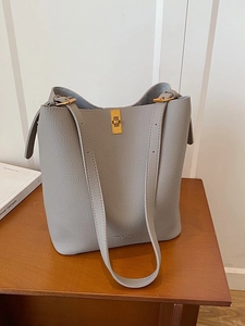 Chic grey litchi grain leather bucket bag with golden buckle on a wooden desk