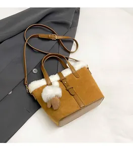 Close-up of brown suede bucket bag featuring white faux fur trim and gold hardware