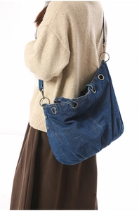 Deep blue denim tote bag detail featuring large silver eyelets and a draped silhouette