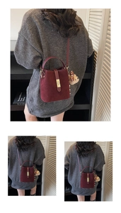 Detail of burgundy suede bucket bag with gold clasp, adjustable strap and bear charm