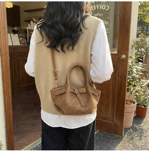 Sac bandoulière en daim marron avec matelassage en losanges et chaîne dans la rue