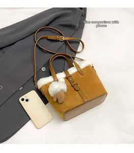 Brown suede crossbody bag with plush trim and adjustable strap for size reference