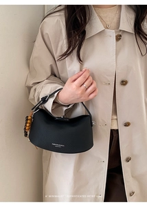 Detail of black pebble leather handbag with short strap and stylish wooden bead charm