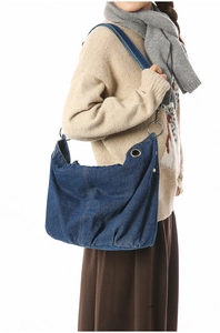 Detail of blue denim hobo bag with large metal rings and contrast stitching detail