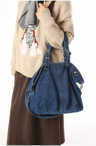Close-up of durable dark blue denim tote bag with metallic adjustable buckle and grommets