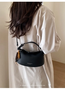 Detail of black lychee leather crossbody bag with vintage wooden beads and shoulder strap