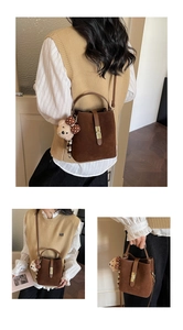 Detail of dark brown matte bucket bag with golden buckle and cute teddy bear charm accessory