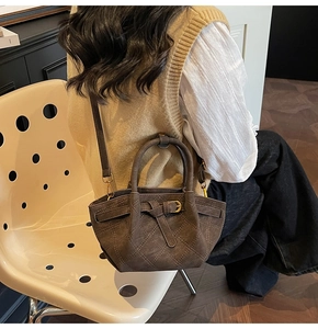 Sac à main matelassé en daim marron avec bandoulière porté par un mannequin en automne