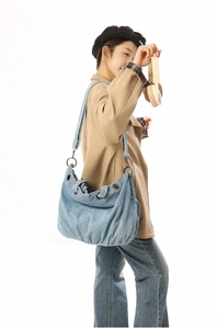 Detail view of large light blue denim tote bag with retro metal rings and rivets detail