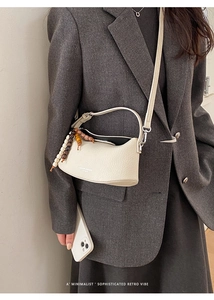 Detail of cream crescent bag featuring lychee texture leather and beaded charm