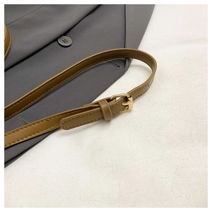 Detail of adjustable tan leather shoulder strap with a polished gold metal buckle
