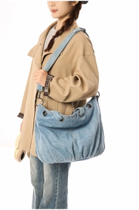 Detail of light blue denim hobo bag with vintage metal grommets and soft washed texture