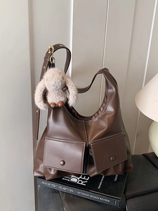 Large vintage brown leather tote bag with functional pockets and plush rabbit charm