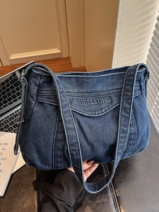 Deep blue denim tote bag with letter embroidery on leather surface with laptop shadow