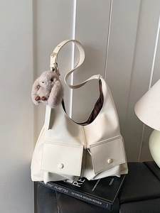 Large cream faux leather tote bag with front pockets and plush rabbit charm on side