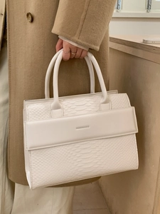 White snakeskin embossed leather tote bag with top handles shown in a fashion lifestyle context
