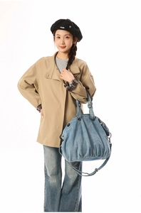 Detailed view of large blue denim tote bag styled with khaki jacket and black beret