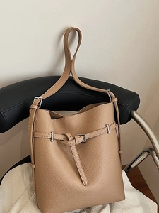 Minimalist camel pebble leather bucket bag with silver buckle on a chair