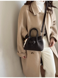 Detail of dark brown matte leather bag with wood bead charm on beige wool coat