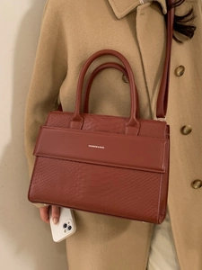 Fashionable brown crocodile pattern tote bag with shoulder strap shown on wool coat