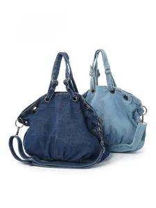 Detail view of denim canvas bags in dark and light blue with metallic eyelets and strap
